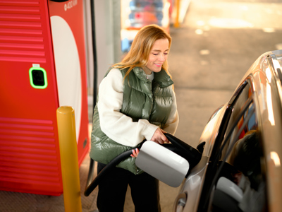 Kvindelig elbilist sætter ladestikket i bilen ved en af Circle K’s lynladere.