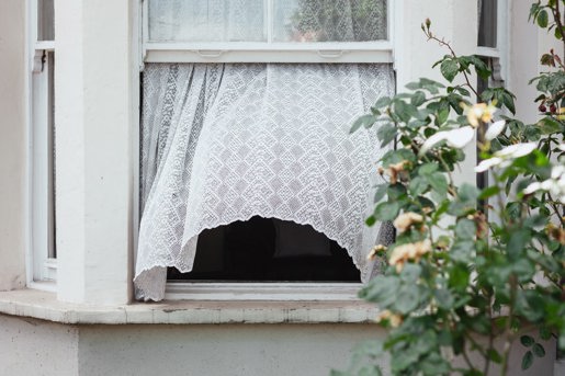 Åbent vindue med et hvidt, blafrende gardin 