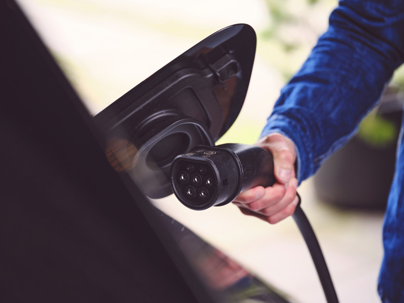 Mand er ved at sætte ladekabel i bil