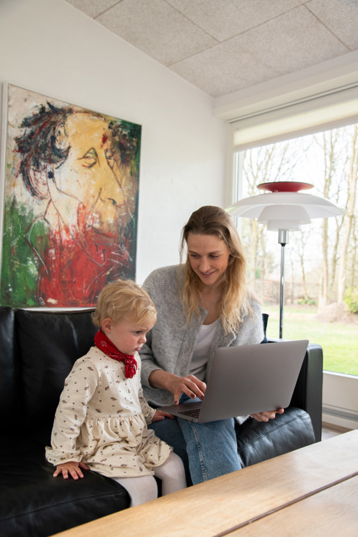 Kvinde sidder med computer sammen med sin datter
